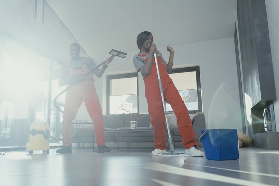 Two adults joyfully clean a modern home interior using a vacuum and mop, creating a lively and clean atmosphere.